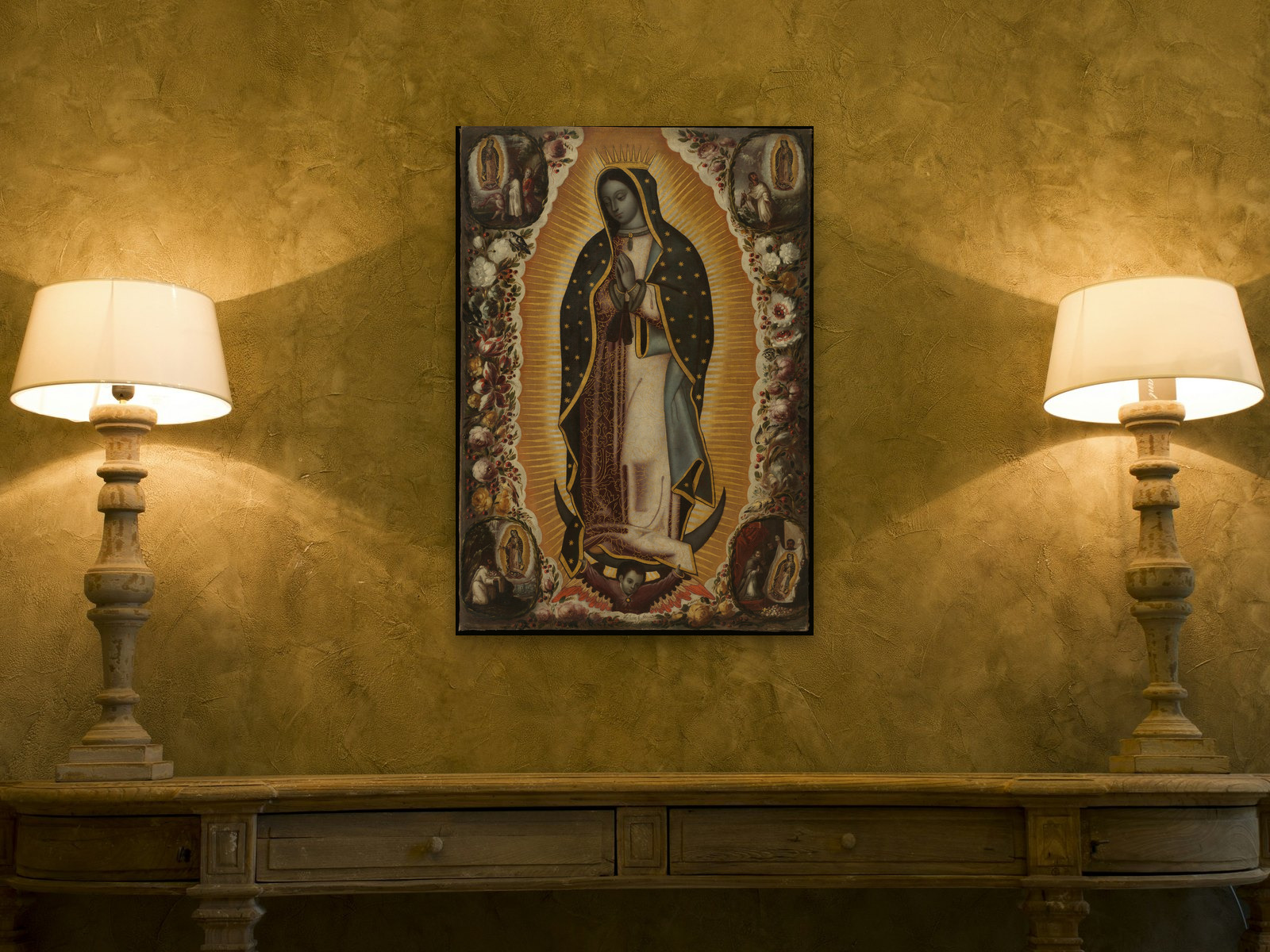 A carved console between two lit lamps against a gold plaster wall; above it the Virgin of Guadalupe by Antonio and Manuel de Arellano, printed at 24 by 36 inches